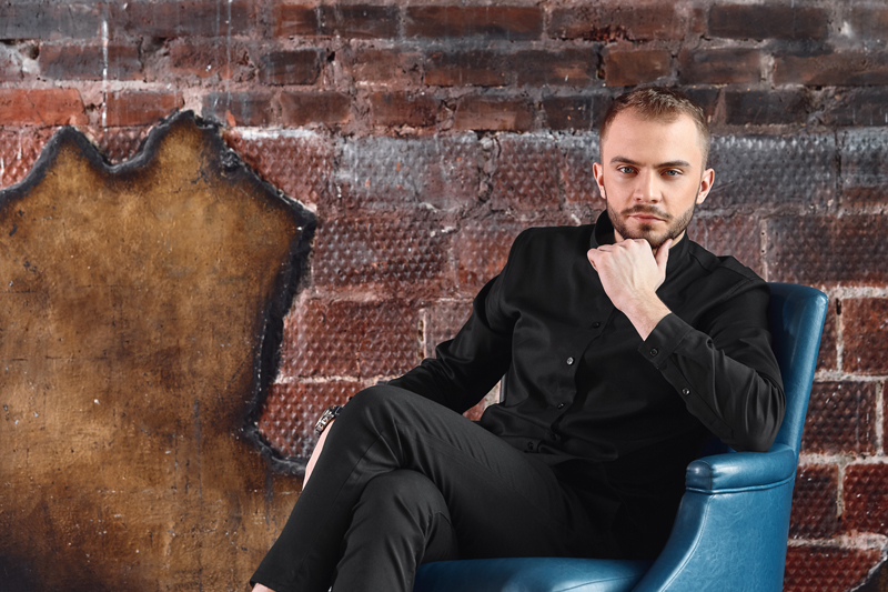 A young man in an armchair in a loft room is looking at the camera. Facing difficulties, not afraid of difficulty. Take responsibility. copies of the space