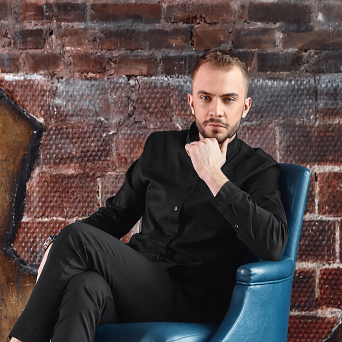 A young man in an armchair in a loft room is looking at the camera. Facing difficulties, not afraid of difficulty. Take responsibility. copies of the space